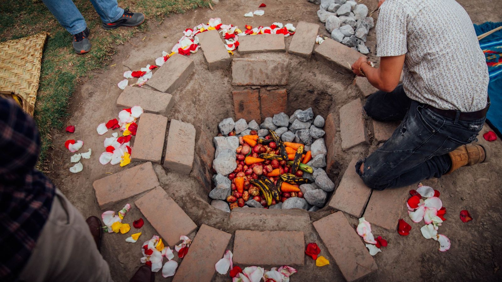 Fosa de ladrillo con piedras, verduras y pétalos para una ceremonia